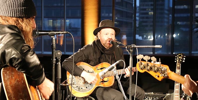 Blackie and the Rodeo Kings three musicians on a stage singing and playing guitar